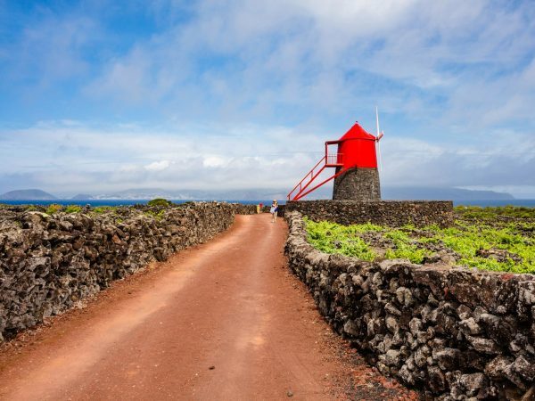 A red windmill stands amidst a beautiful landscape.